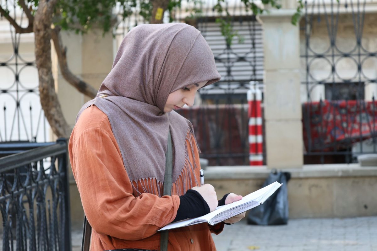 Jeune femme debout dans une rue écrivant dans un carnet