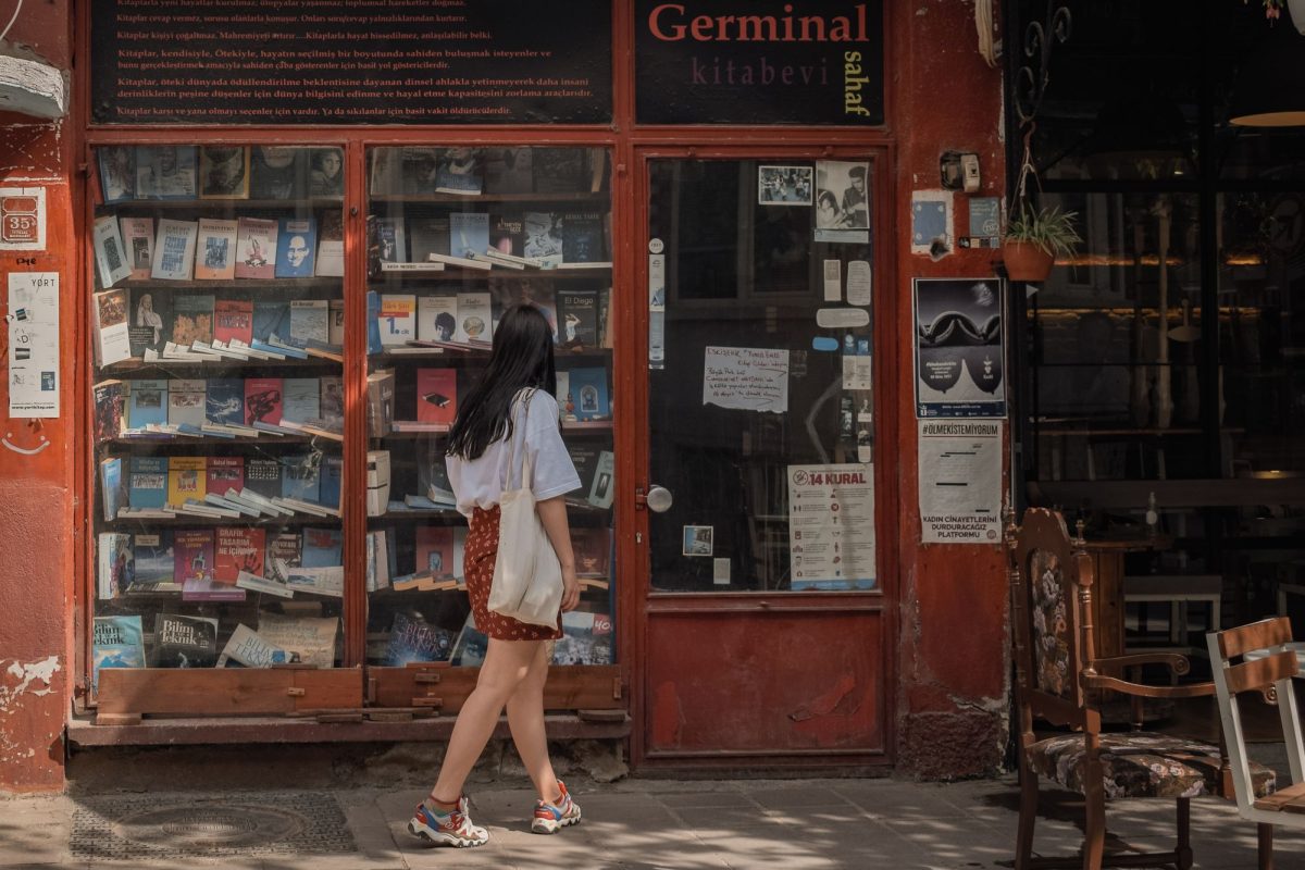 Jeune femme passant devant la vitrine d'une librairie à la façade rouge