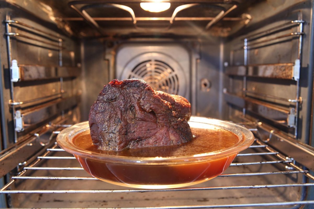 Rôti de viande dans un plat en verre posé sur la grille d'un four à chaleur tournante