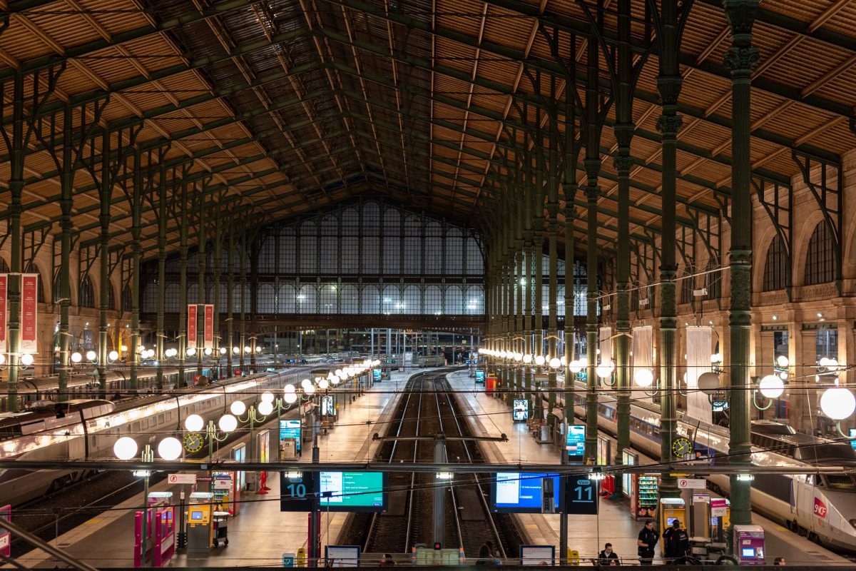 Grande halle vitrée de la gare du Nord à Paris avec ses quais et ses panneaux de départ