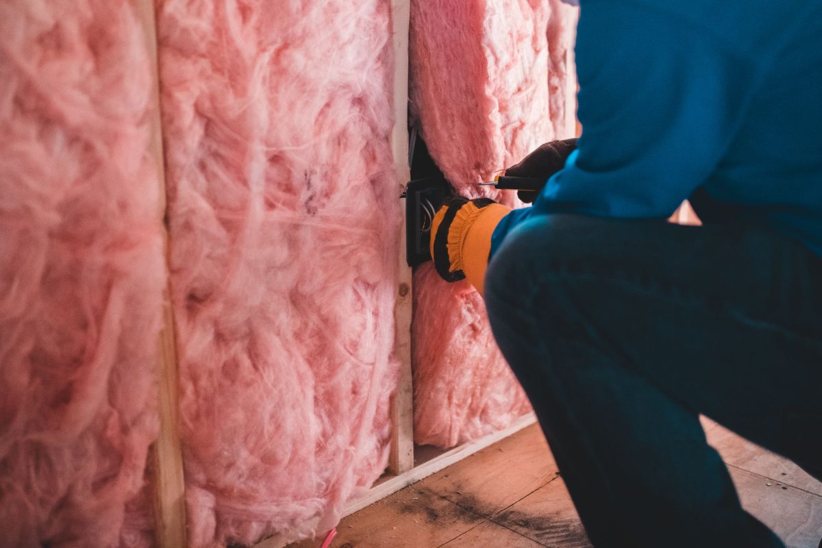 Ouvrier posant de la laine de verre rose dans un mur pour isoler une maison