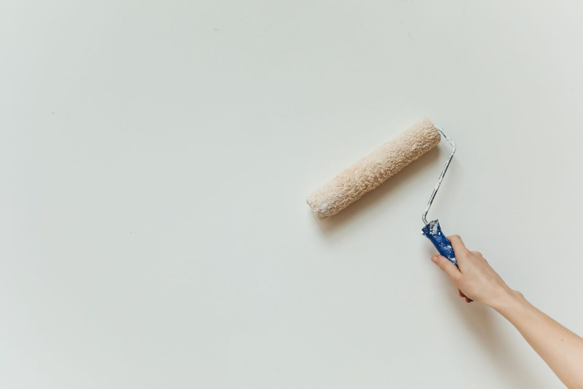 Main passant un rouleau de peinture sur un mur intérieur