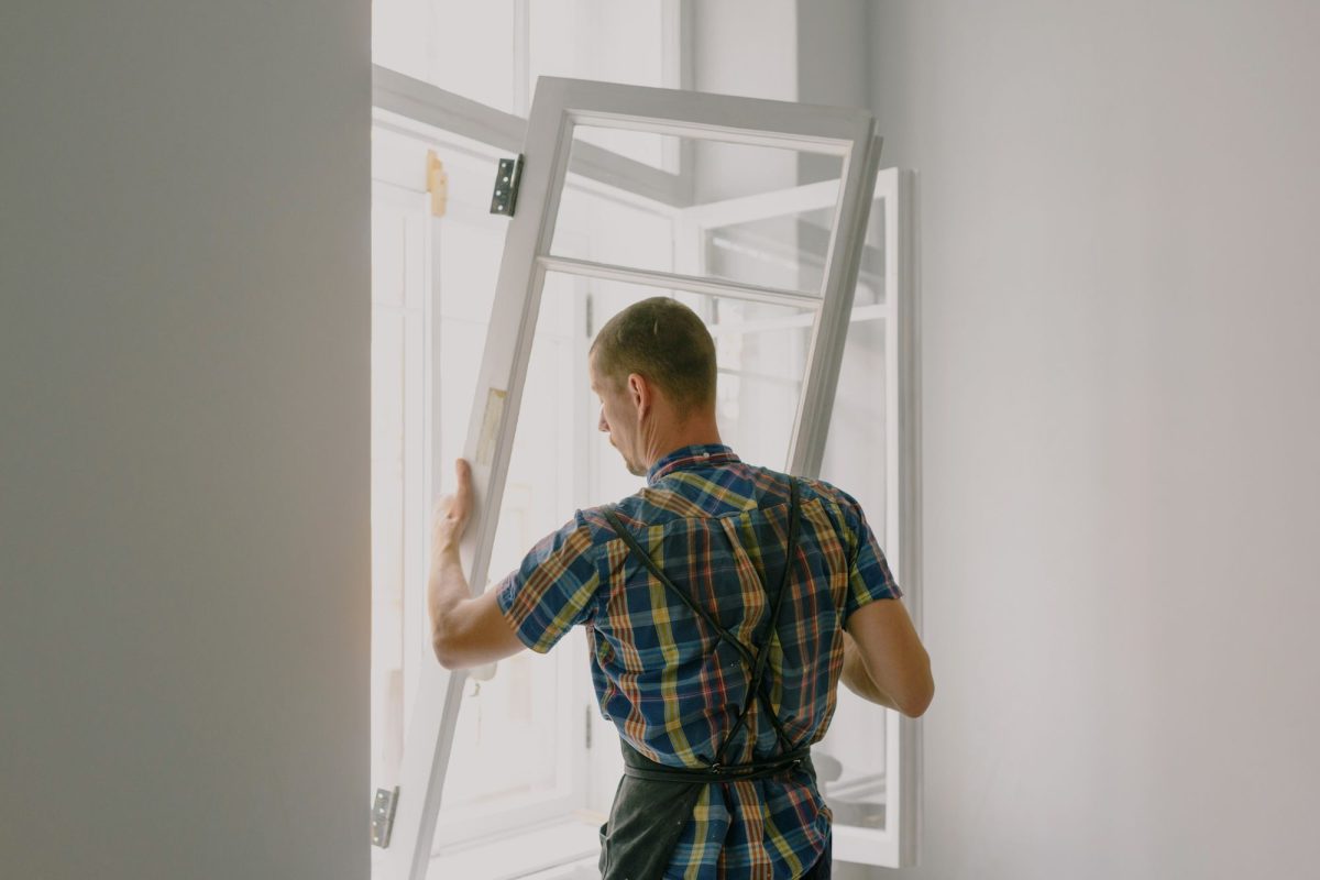 Installateur posant un cadre de fenêtre blanc dans un mur