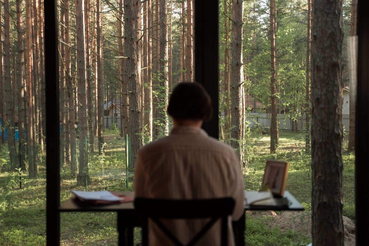 Personne assise à un bureau face à une forêt, dans une résidence d'écriture