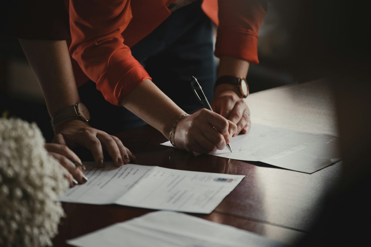 Deux personnes signent des documents à une table lors de la conclusion d'un contrat