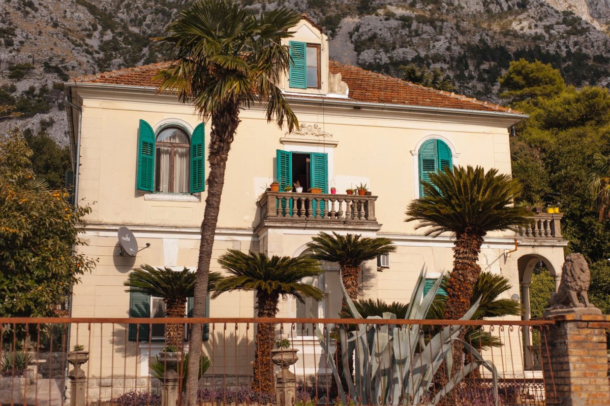 Maison blanche à toit de tuiles au milieu de palmiers, type location de vacances